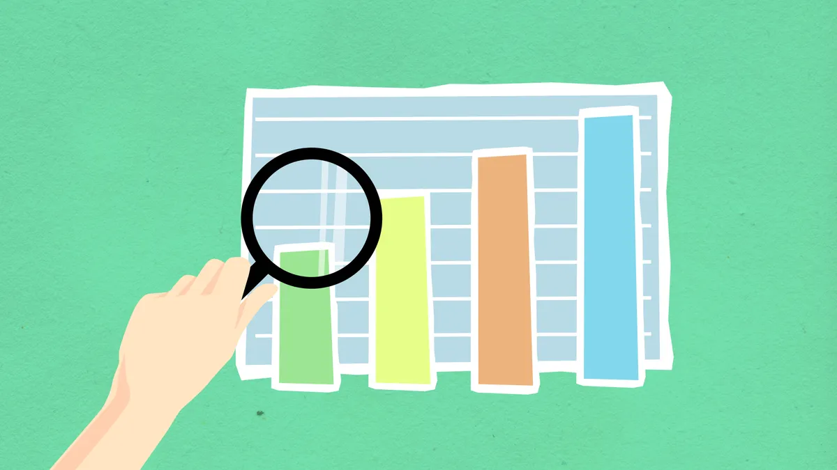 Hand using magnifying glass on a bar chart