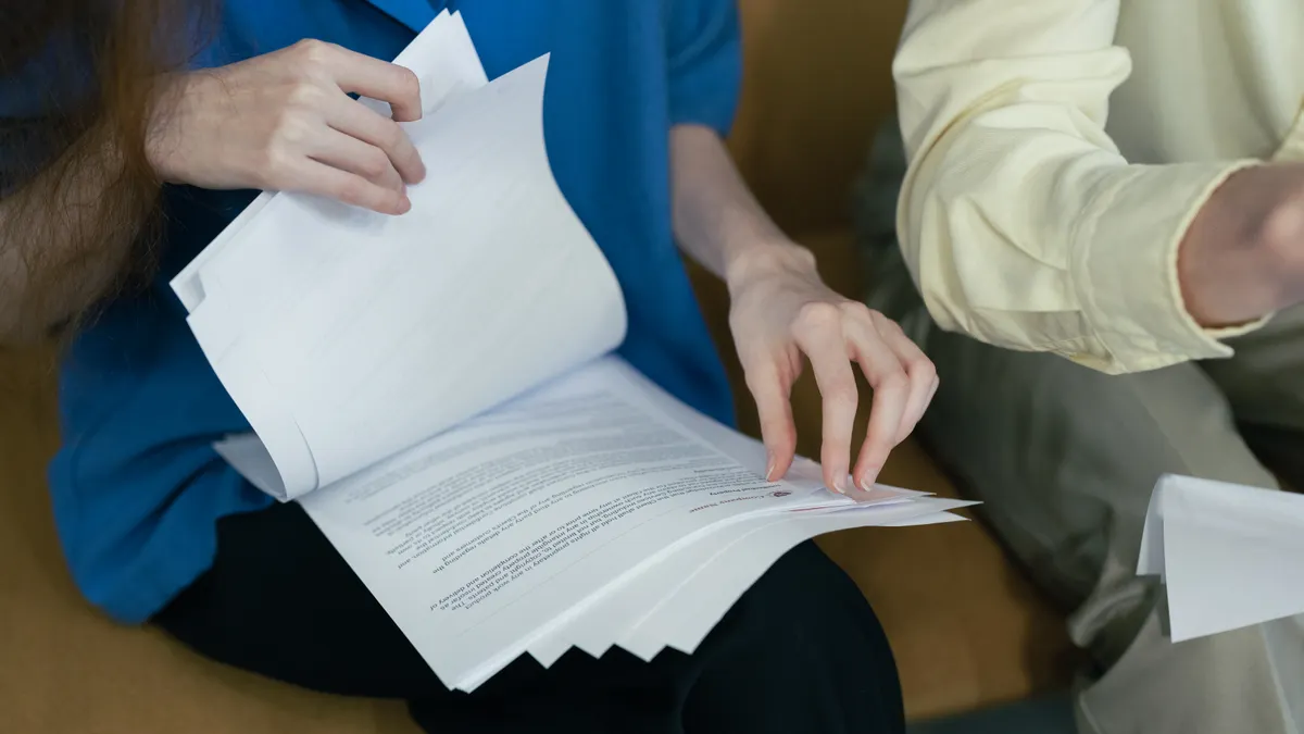 Two people reviewing a stack of printed documents